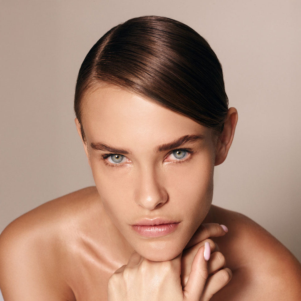 Woman with a neutral expression against a beige background